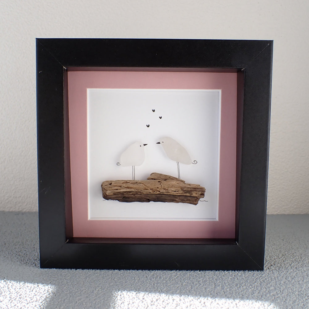 
                  
                    framed picture of two sea glass birds sitting on apiece of driftwood

                  
                