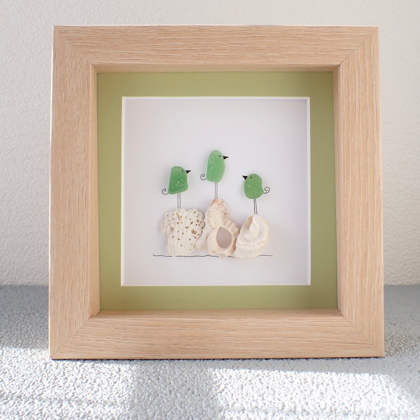 framed picture of Three Colorful Sea Glass Birds on Washed shells and coral