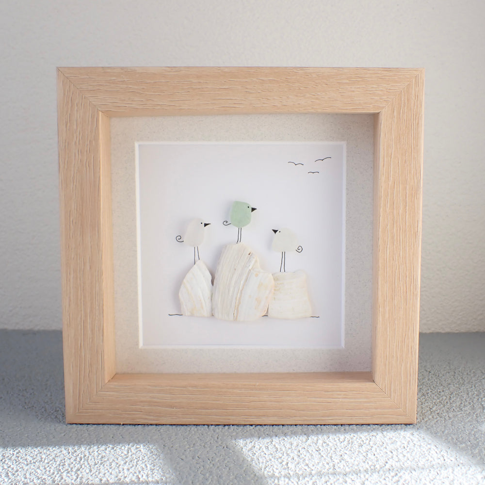 framed picture of three birds sitting on broken clam shells
