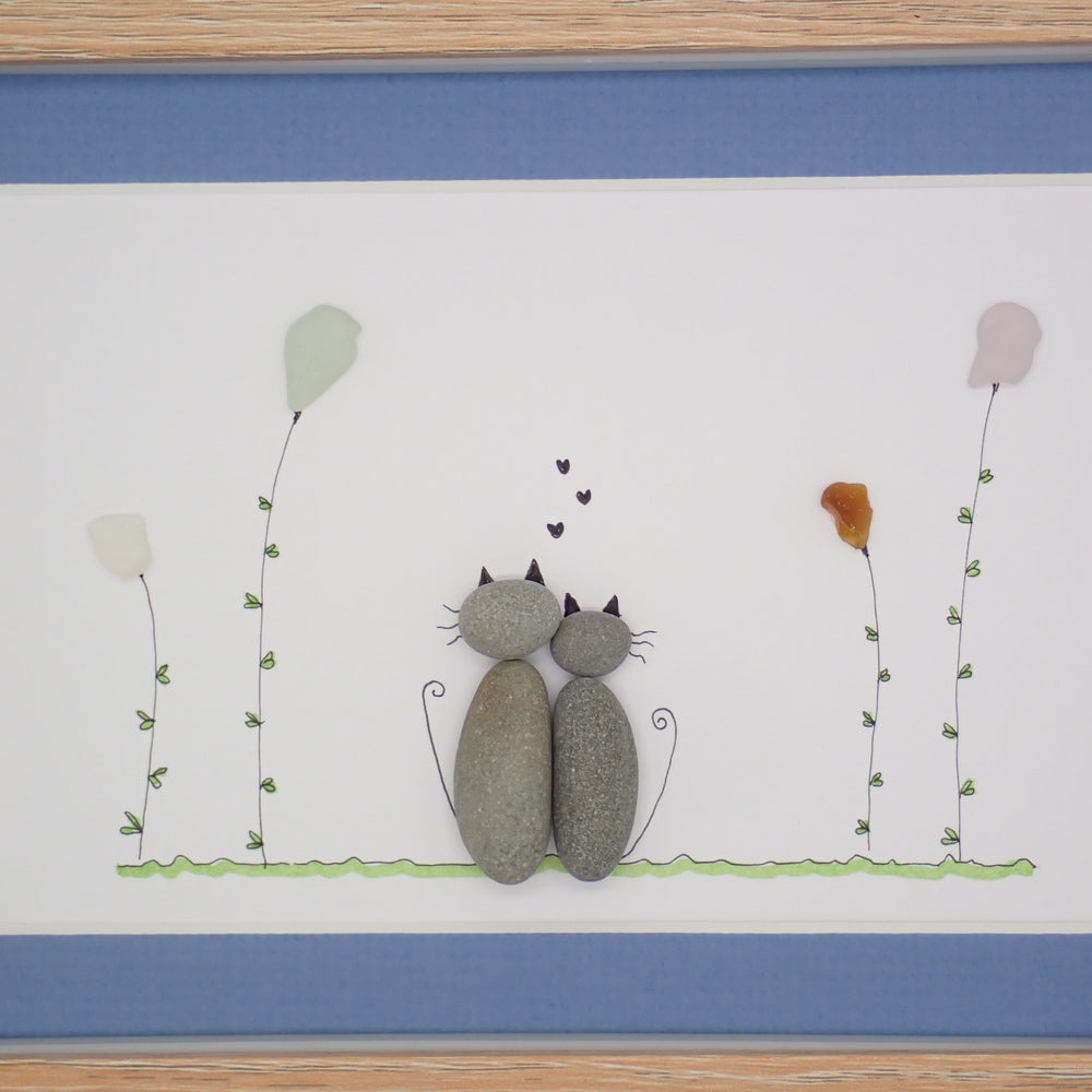 sea glass art features two cuddling cats sitting in a sea glass garden