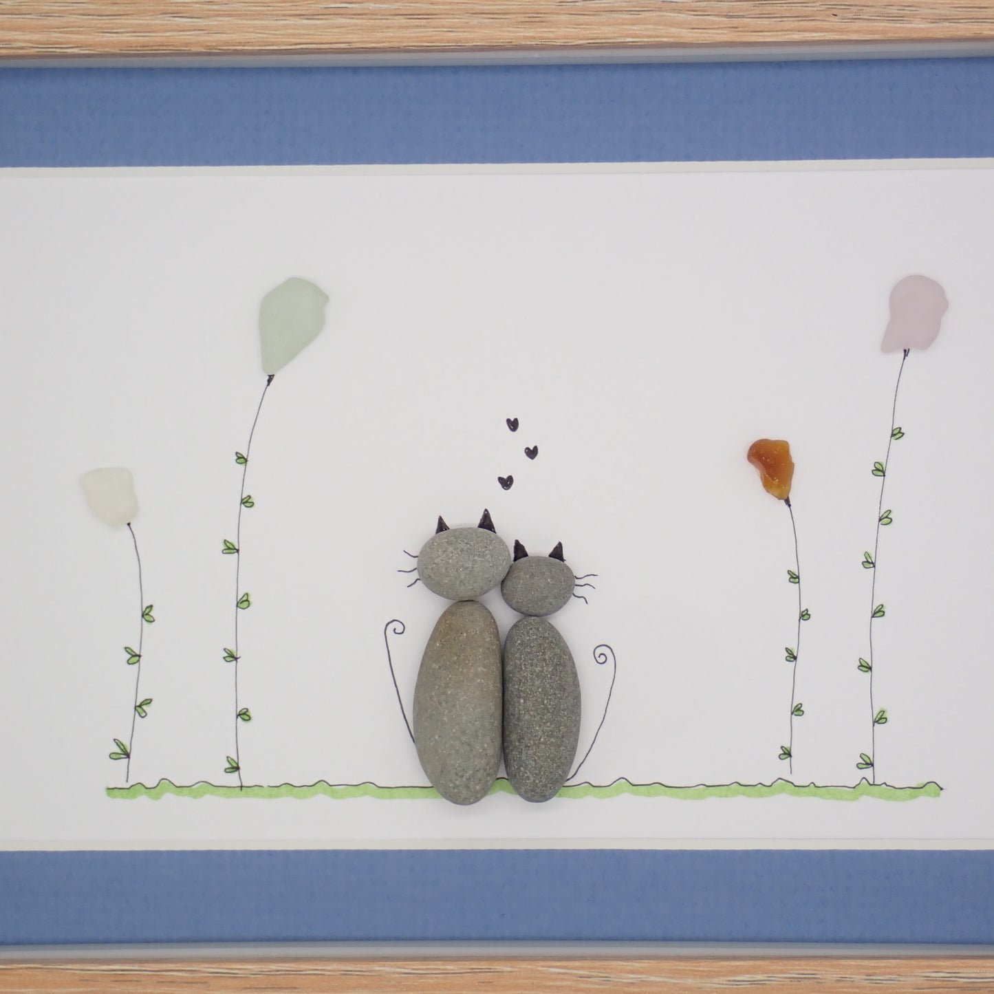 sea glass art features two cuddling cats sitting in a sea glass garden