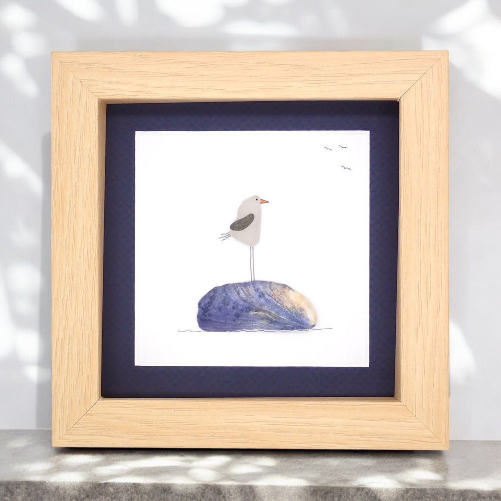 
                      
                        sea glass picture of a seagull standing on a purple muscle shell
                      
                    