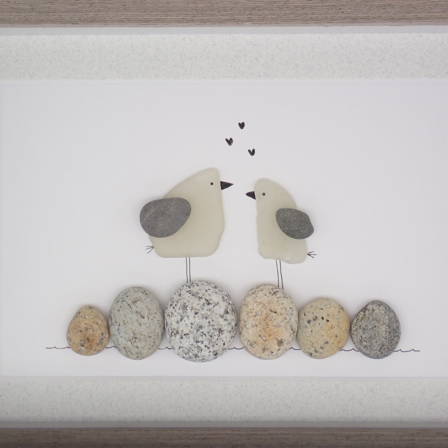 sea glass art features two sea gulls standing on washed pebbles.