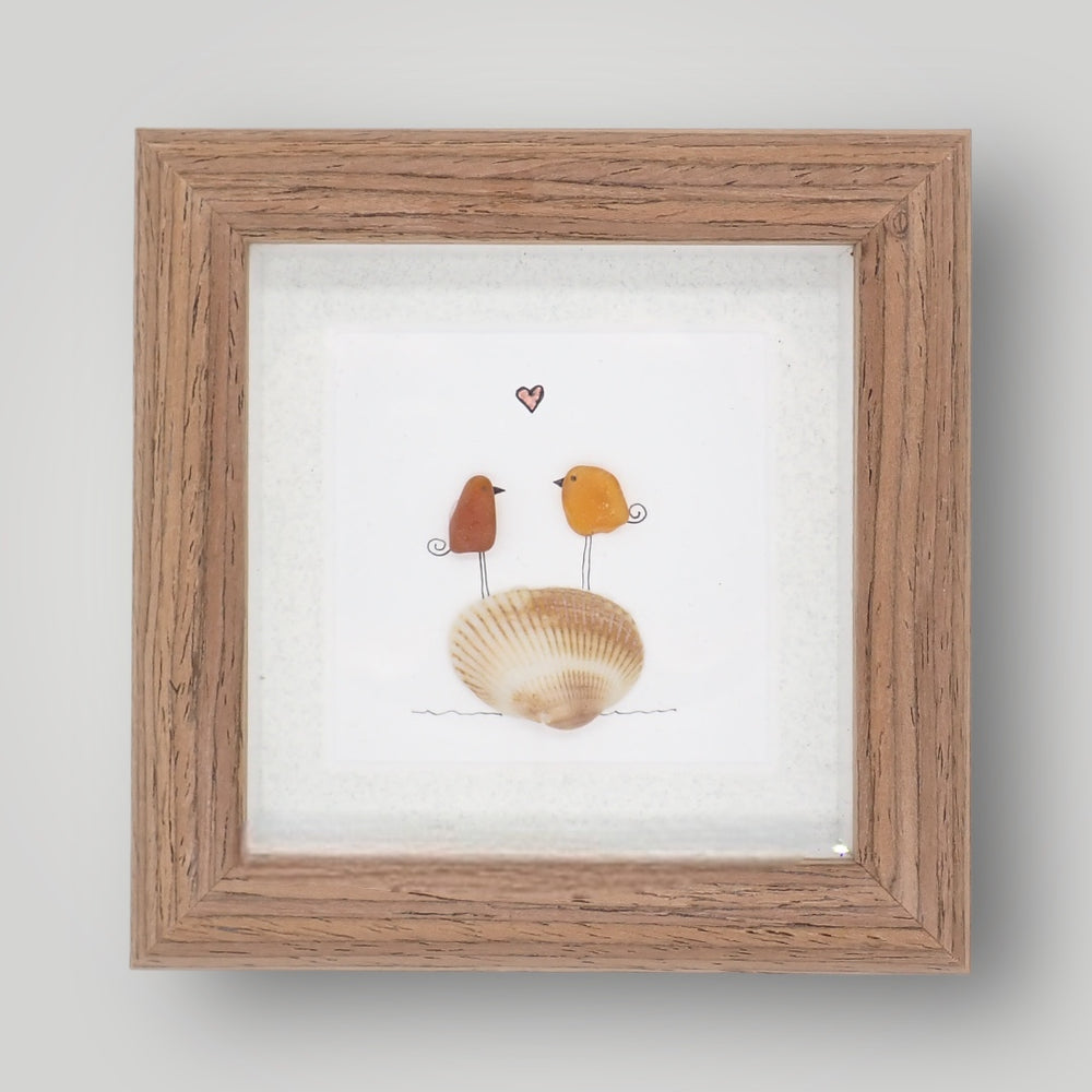 sea glass art features two birds in love standing on a shell