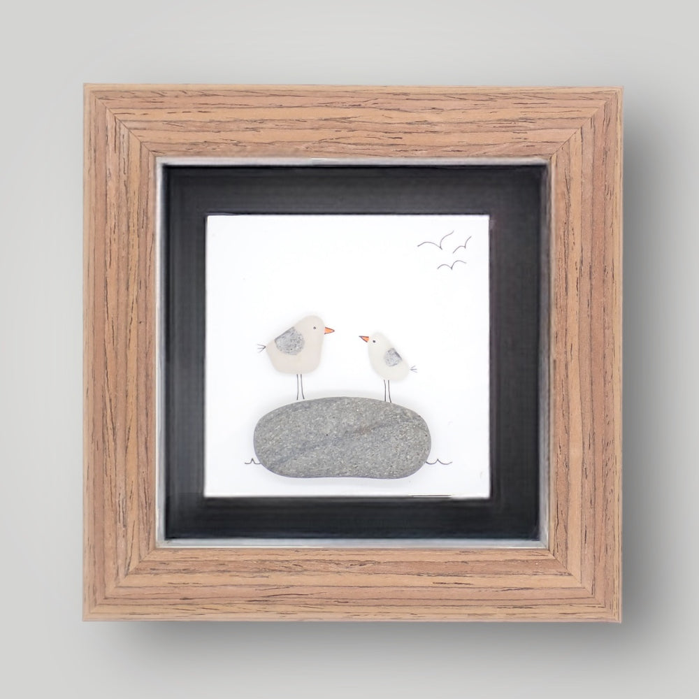 sea glass art features two seagulls standing on a beach pebble