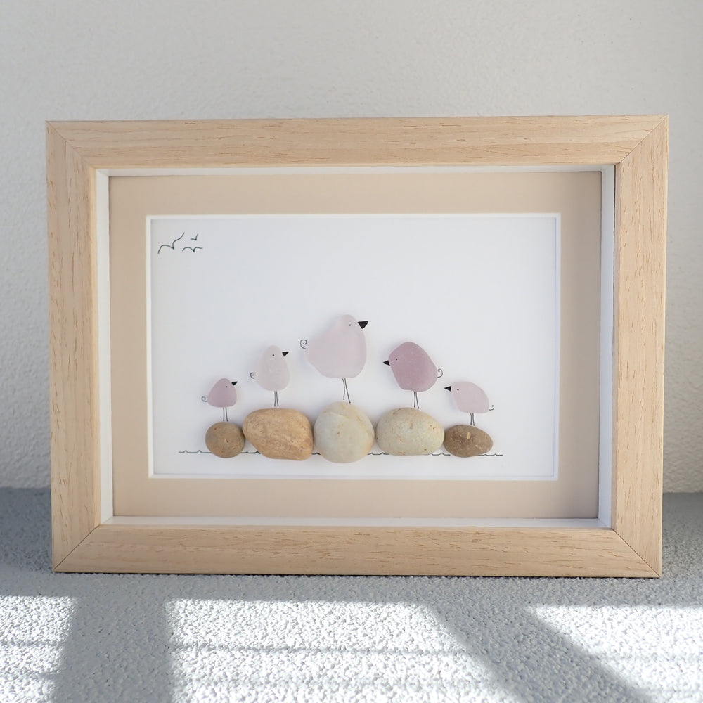 
                  
                    shadowbox frame with a picture of 5 purple sea glass birds standing on beige beach rocks
                  
                