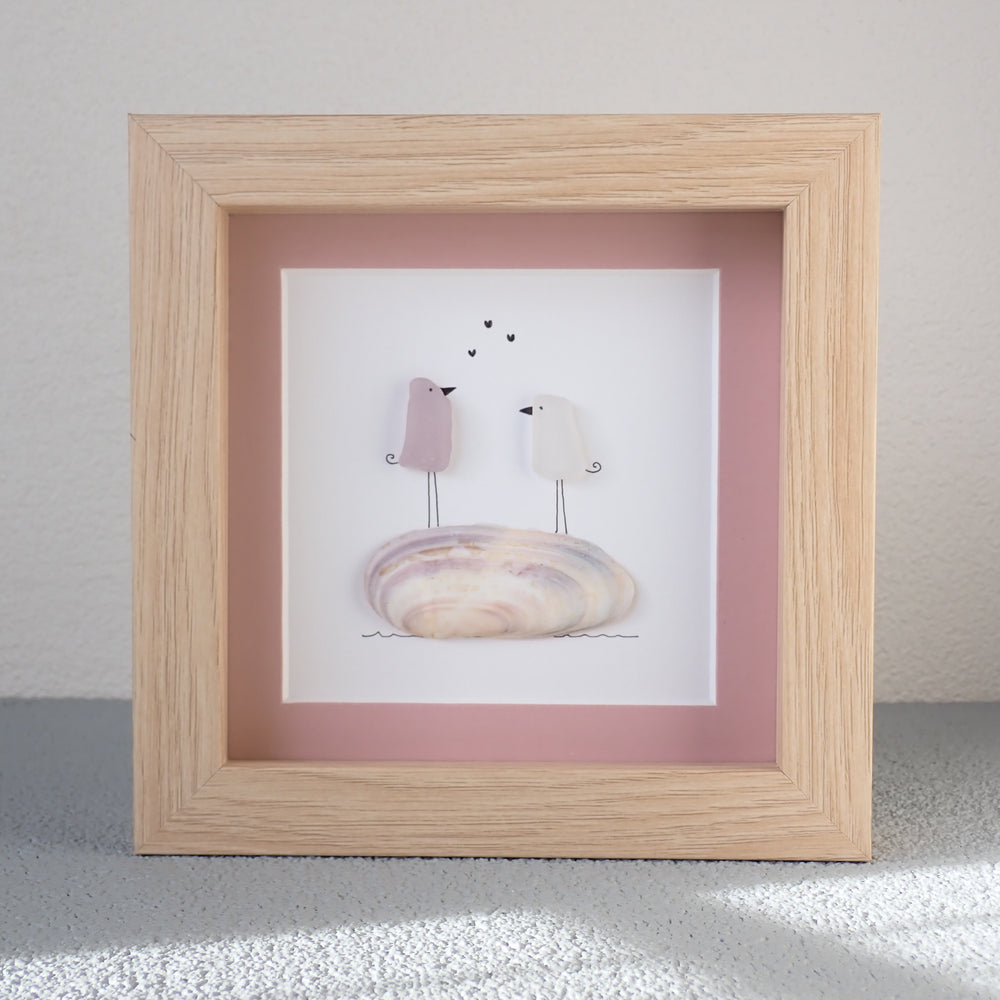 
                  
                    framed picture of sea glass art with love birds standing on a shell.
                  
                