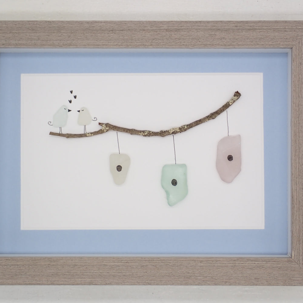 sea glass art features two sea glass birds standing on a branch above bird houses