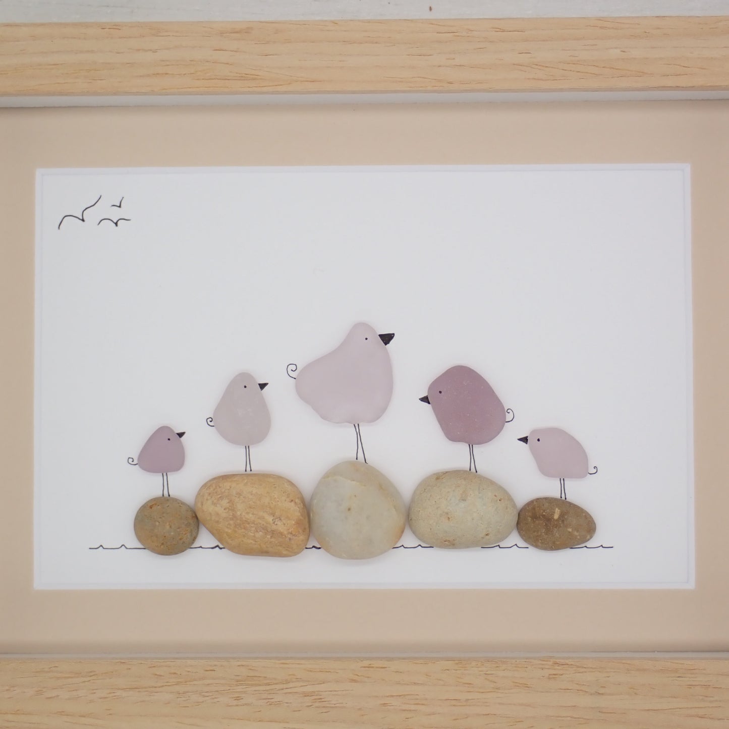 This piece of sea glass art features five purple glass birds standing on washed pebbles.