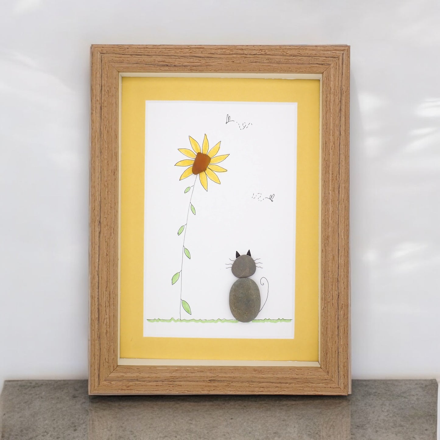 sea glass art features a cat sitting by a sea glass sunflower