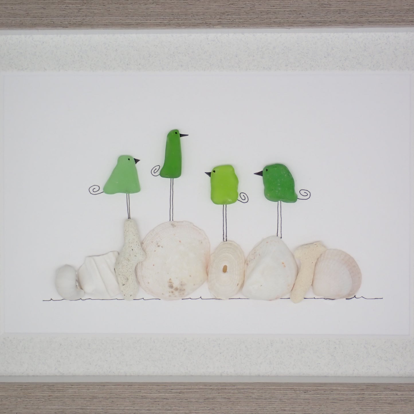 sea glass art features four green glass birds standing on coral and shells