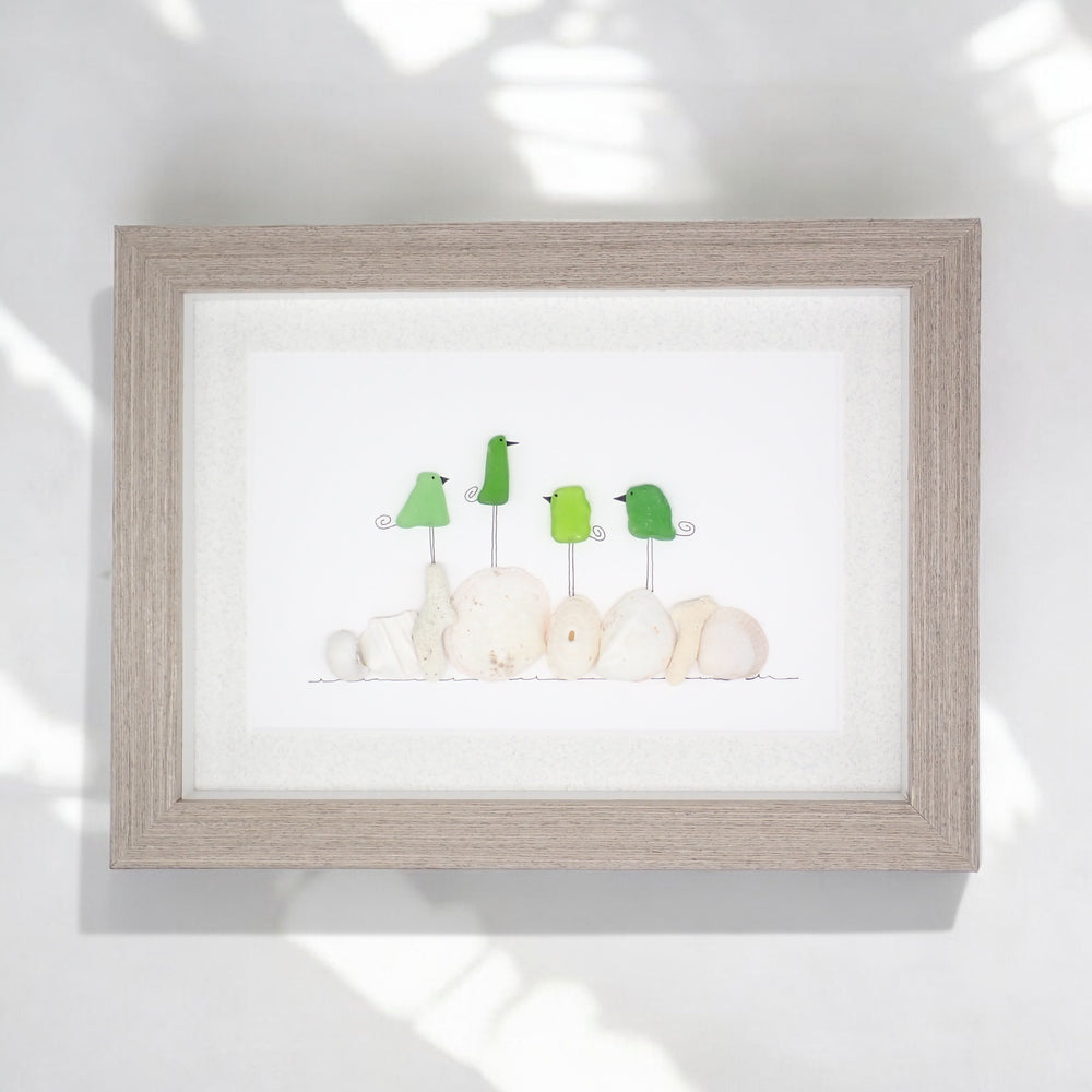 sea glass art features four green glass birds standing on coral and shells