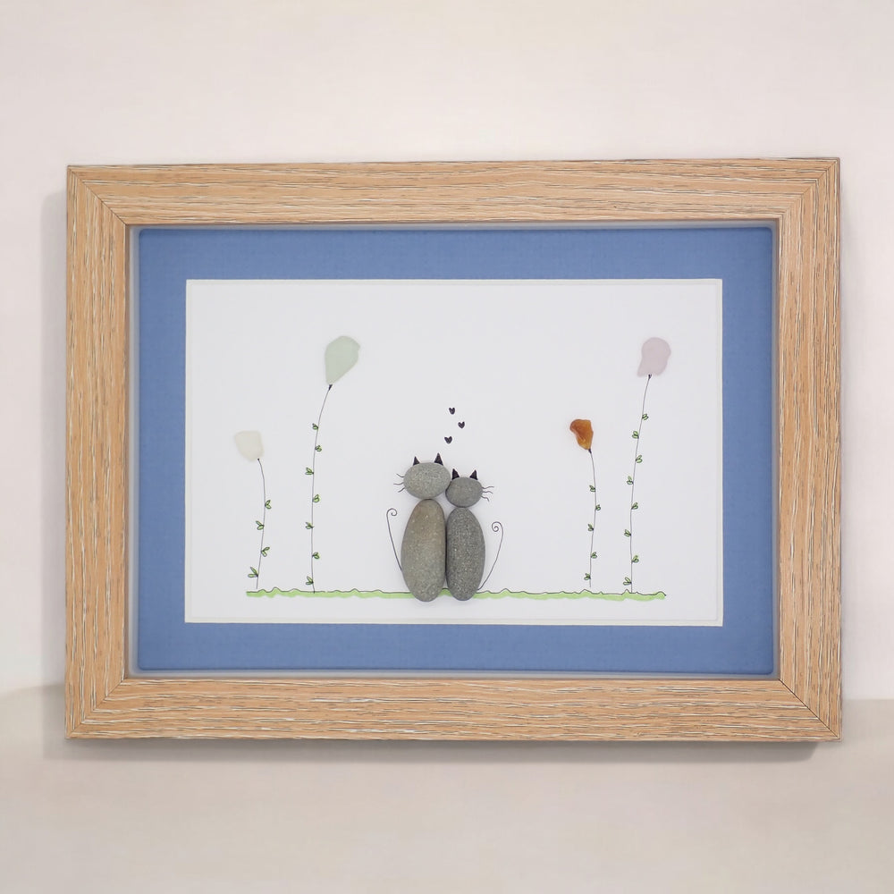 sea glass art features two cuddling cats sitting in a sea glass garden