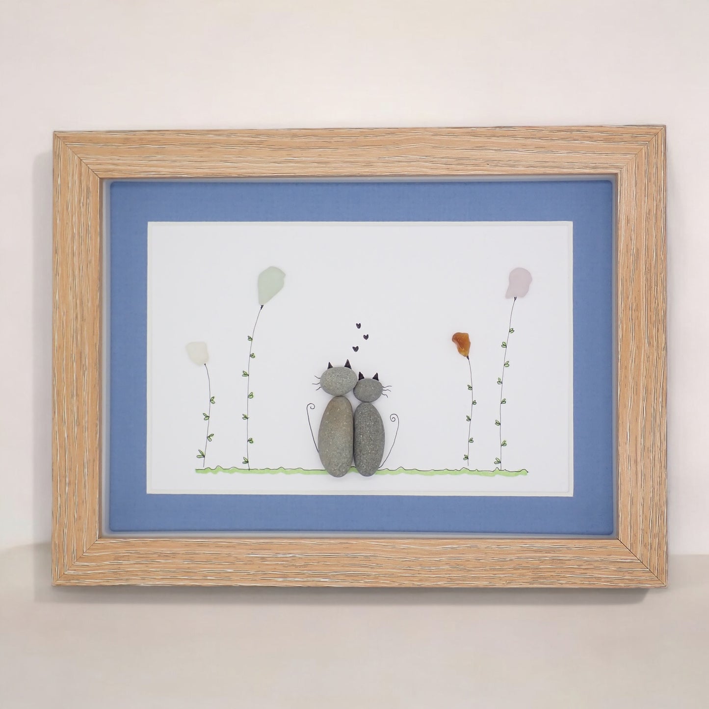 sea glass art features two cuddling cats sitting in a sea glass garden