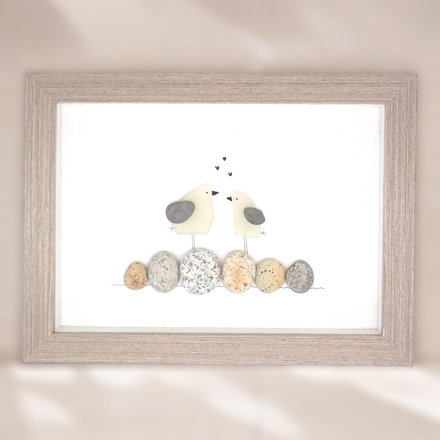 sea glass art features two sea gulls standing on washed pebbles.